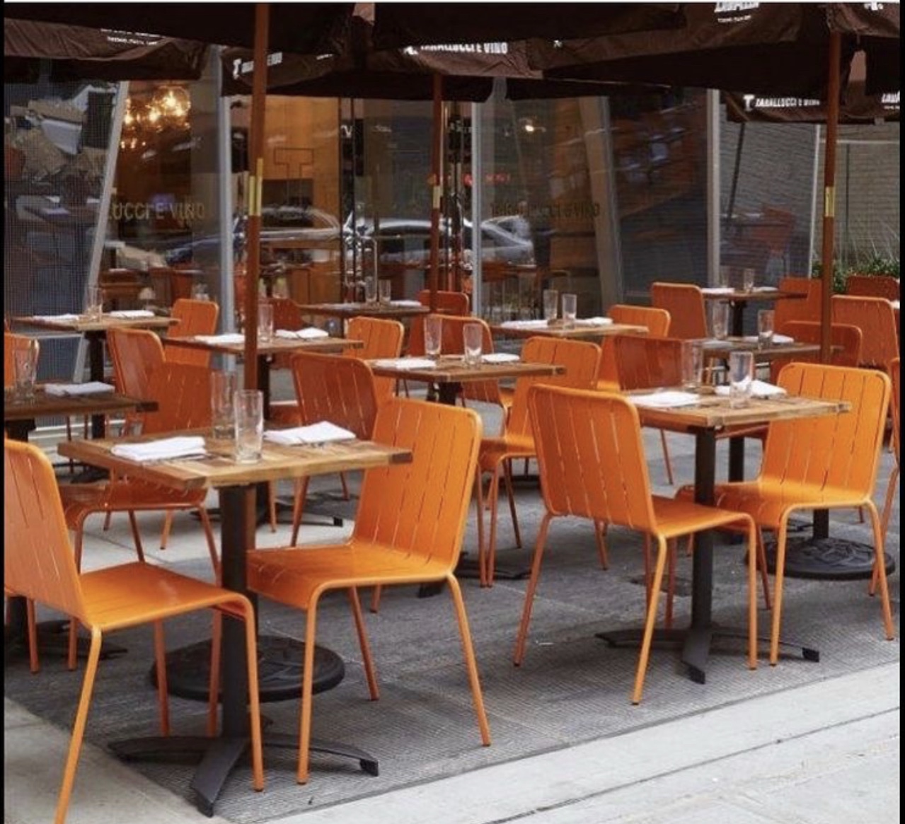 Restaurantterrasse mit orangefarbenen Stühlen und Holztischen